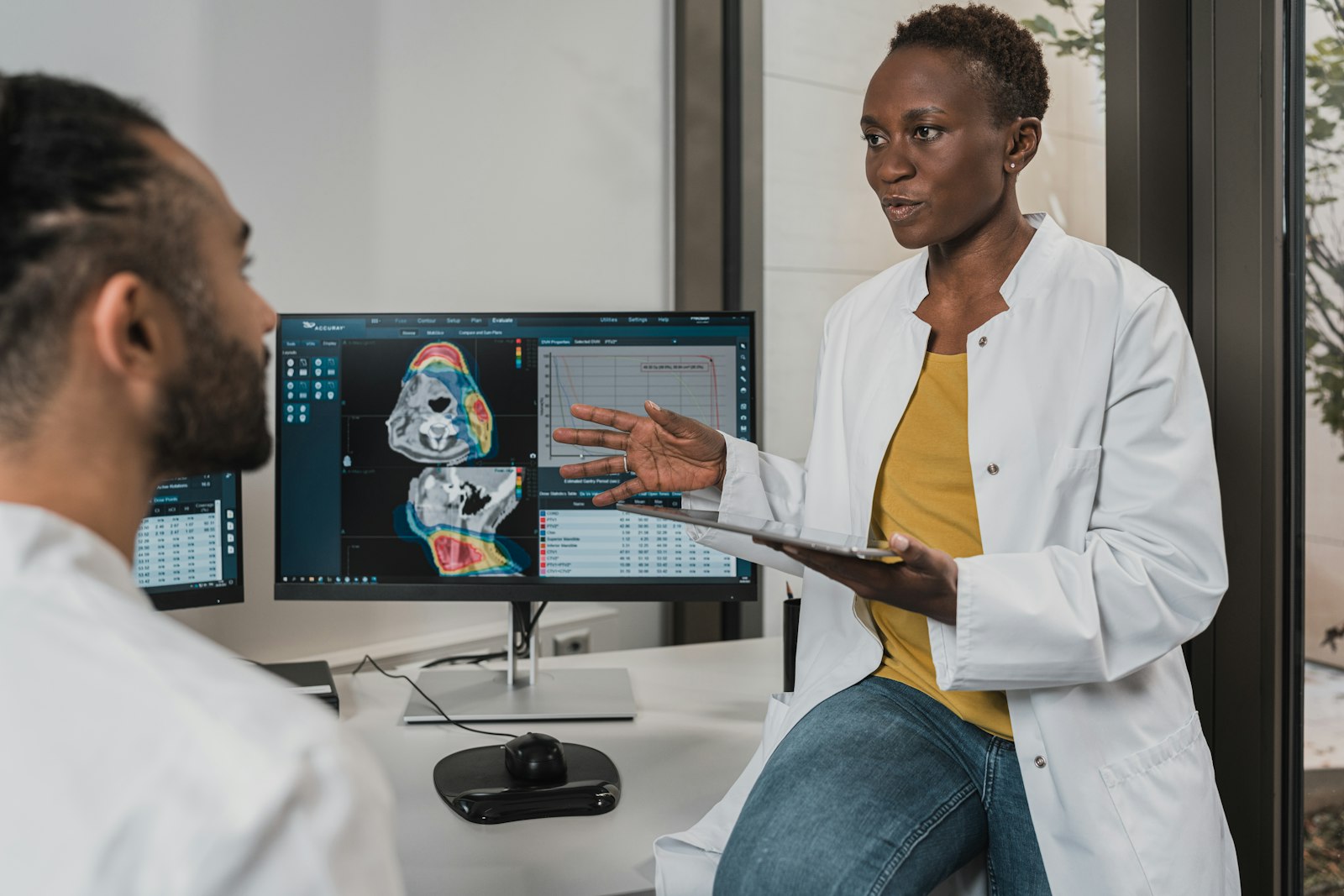 Clinician reviewing radiology planning images on screen with a patient